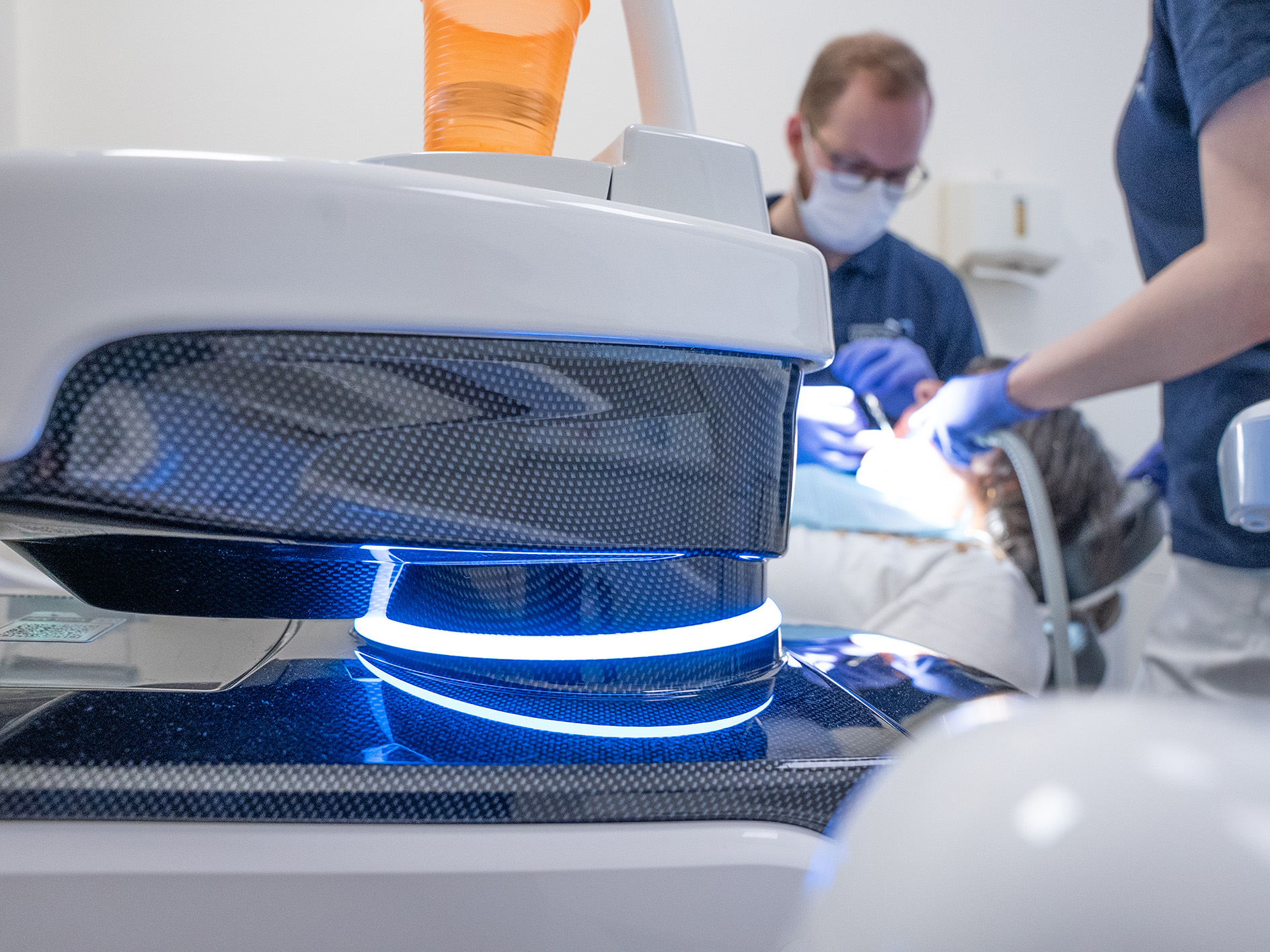 Zahnarzt arbeitet konzentriert an Patient, Gesichtsmasken, weiße und blaue Ausstattung im Fokus.